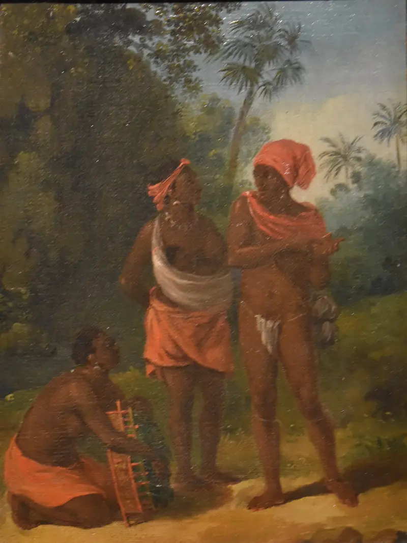 Three figures in vibrant clothing stand in a lush Caribbean clearing, engaged in conversation amidst dense foliage.