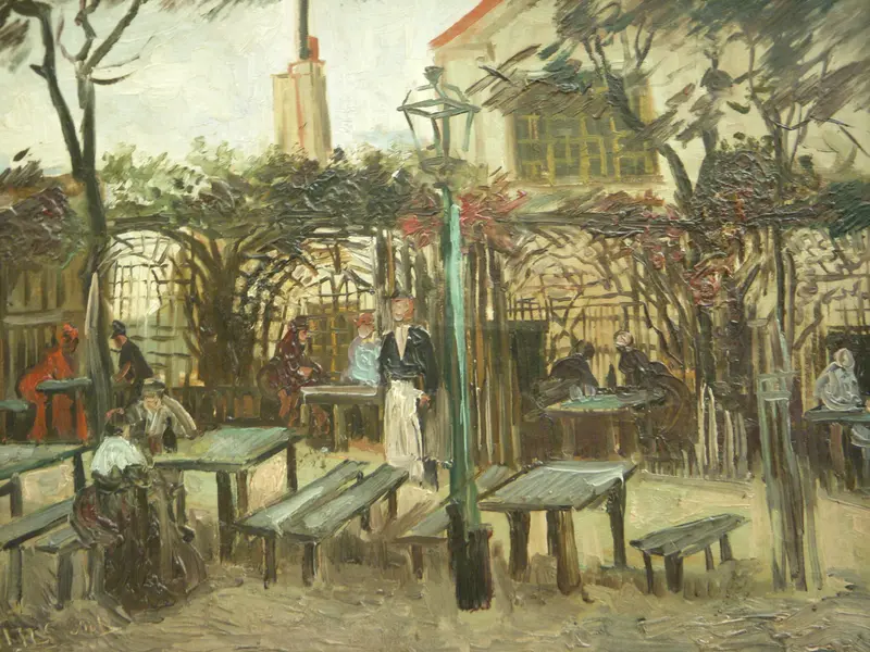 Outdoor café terrace with wooden tables and benches, several seated and standing figures, a green lamppost, and a pale building with a red roof in the background.