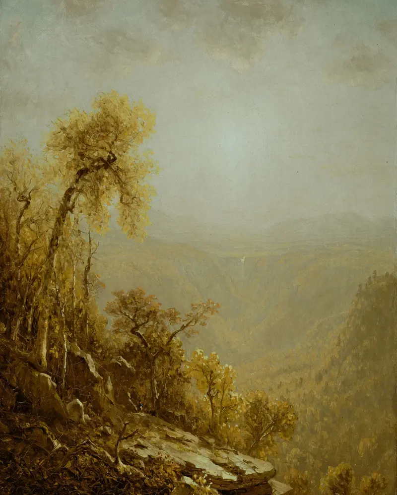 A steep rocky slope covered in golden-leaved trees descends into a vast wooded gorge bathed in golden light with a tiny blue mark near the rocks.