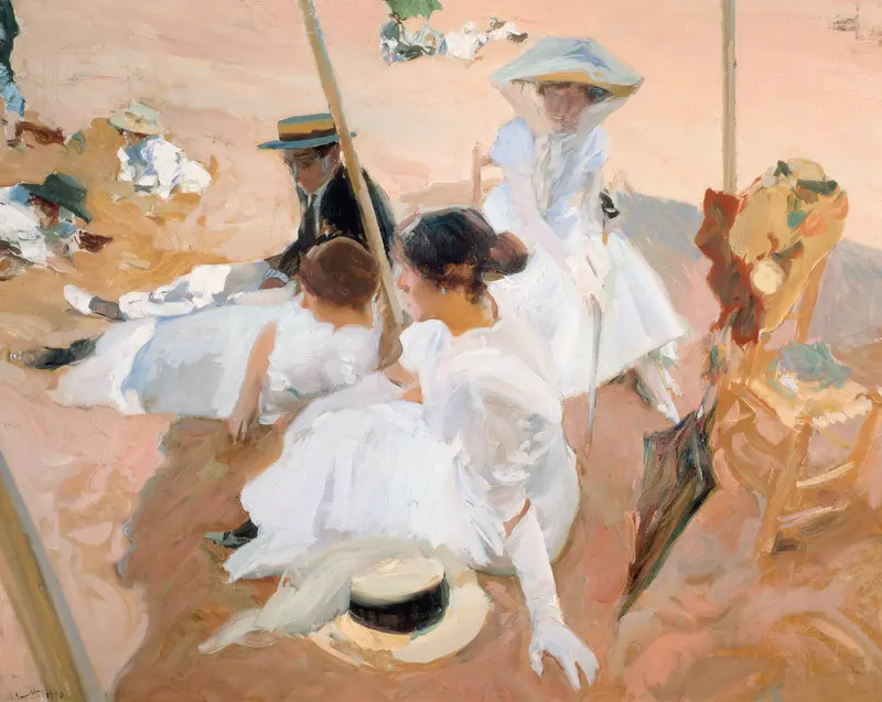 A group of people seated and reclining under an awning on a sandy beach, with children playing in the background and various hats and umbrellas nearby.