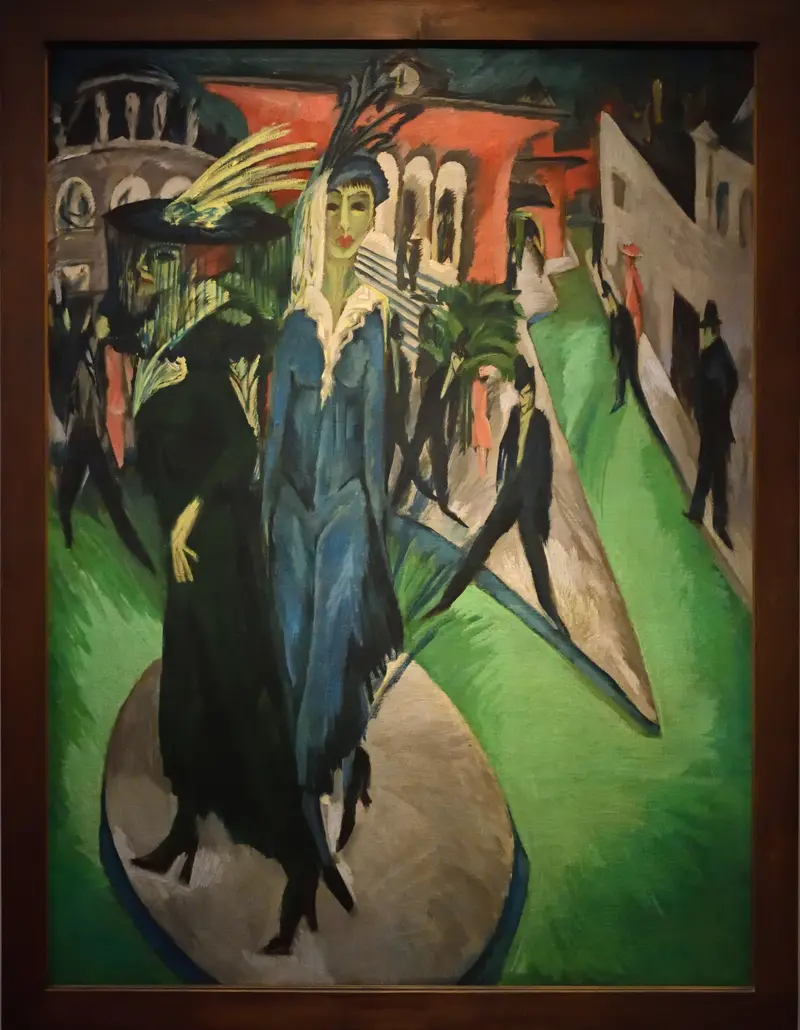 Two women in extravagant hats stand amidst a restless city night, their angular forms and vivid colors contrasting with shadowy figures around them.
