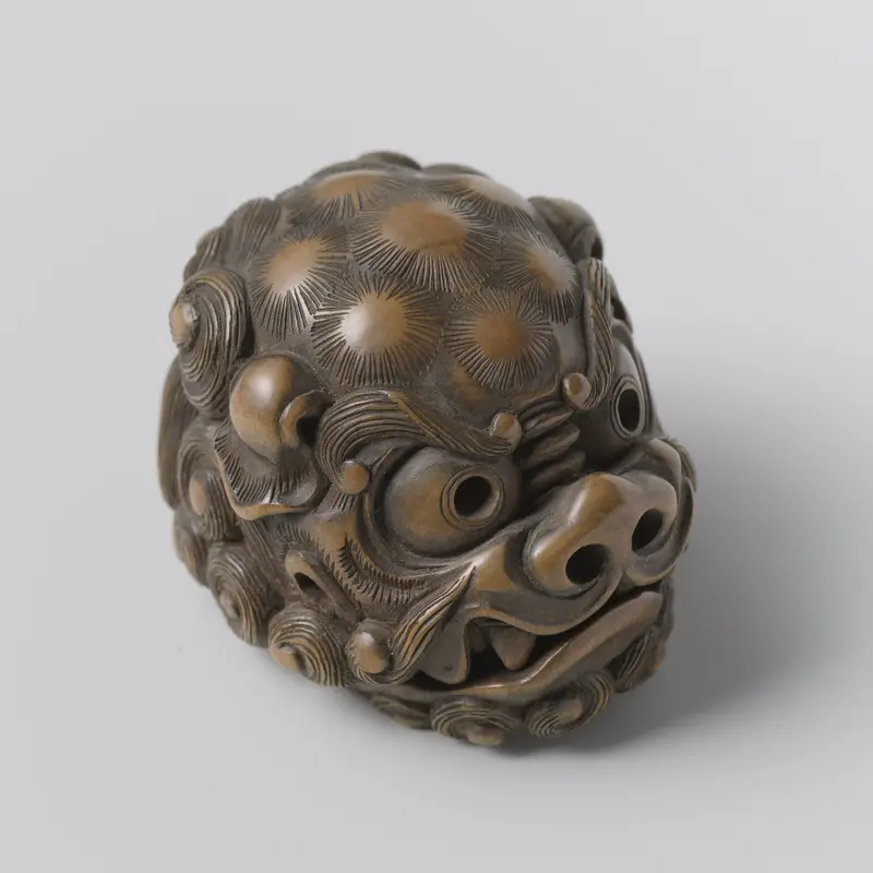 Netsuke sculpture by Tomotada, crafted in wood with intricate detailing.