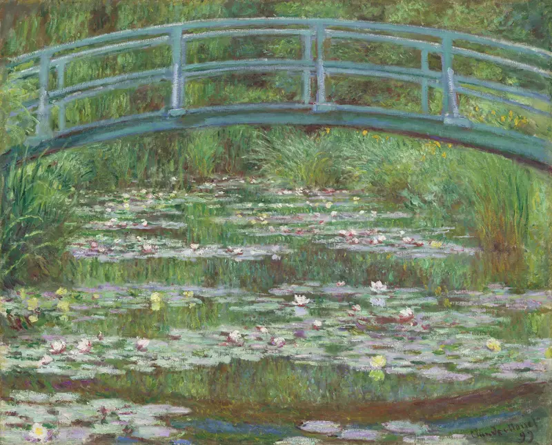 A blue-green curved wooden bridge arches over a pond filled with lily pads and blossoms, surrounded by dense greenery and sunlight reflections.