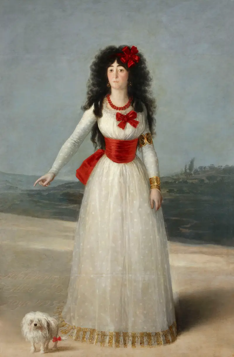 A woman in a white dress with red sashes and bows stands in an open landscape pointing to an inscription on the ground, with a small white dog at her feet.