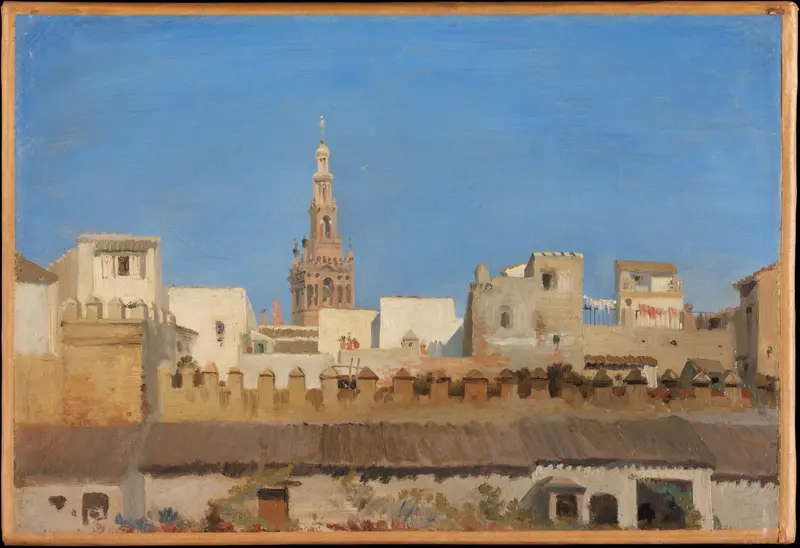 The Giralda tower rises above sun-bleached rooftops in Seville, framed by whitewashed walls and a brilliant blue sky.