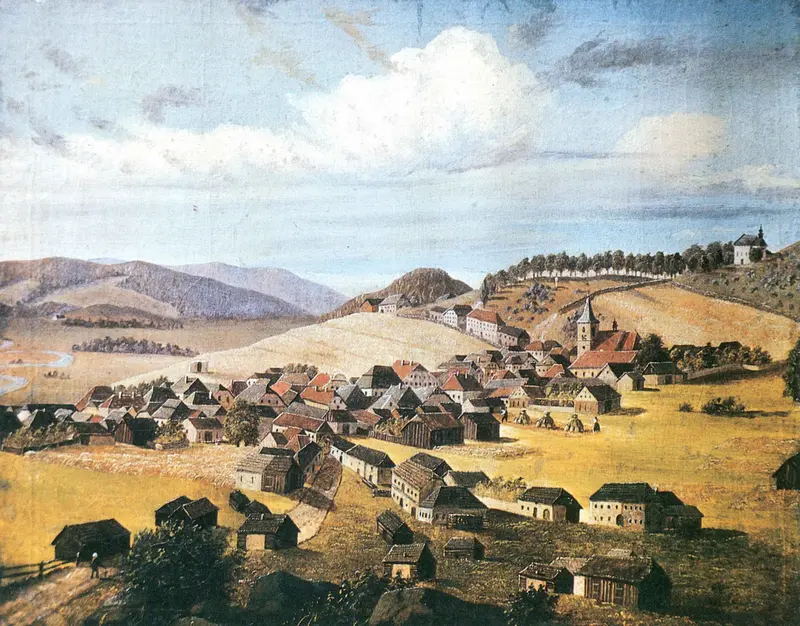 A village nestled in the Bohemian hills, with rooftops and a church spire under a broad sky.