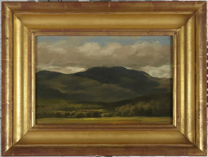 A dark mountain summit partially obscured by clouds, with a glowing green meadow in the foreground.
