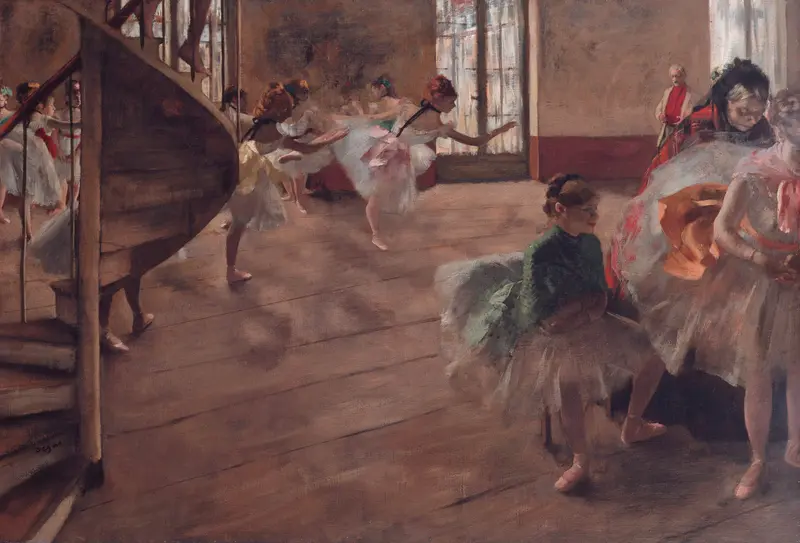 A sunlit rehearsal room shows young ballet dancers in white tutus practicing at the barre beside a spiral wooden staircase, with two seated girls resting nearby.