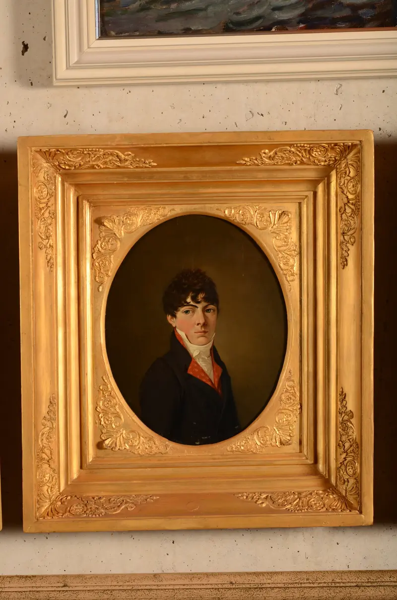 A young man in a white collar and red waistcoat gazes directly at the viewer against a dark background.