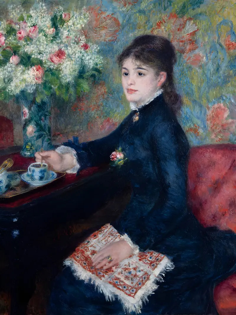 A young woman in a deep blue dress sits in profile on a red-cushioned chair holding a spoon over a blue-and-white cup on a small black table, with a large vase of white and pink flowers behind her.