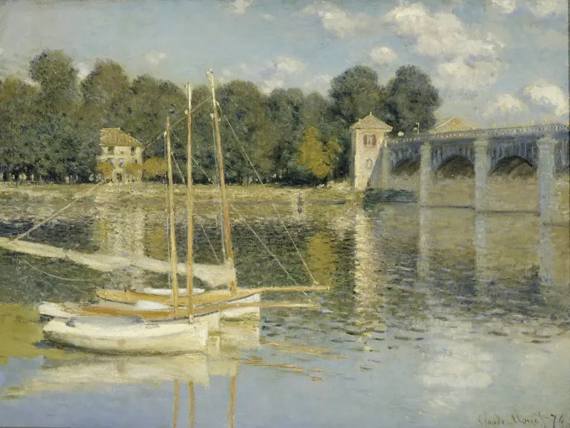 Two white sailing boats moored on the Seine in front of a stone railway bridge with five arches and leafy riverbanks under a cloudy sky.