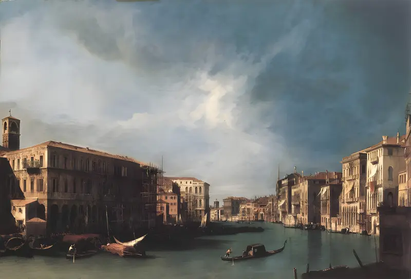 A gondola glides on the Grand Canal with boats moored along the banks, Venetian palazzi on the right, and a large building with a bell tower on the left under a sky filled with blue and white clouds.