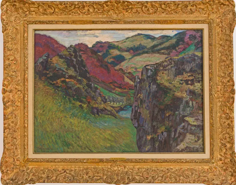 A vibrant landscape with hillsides in reds and violets, a dramatic rock face, and a blue ribbon of water in the valley.