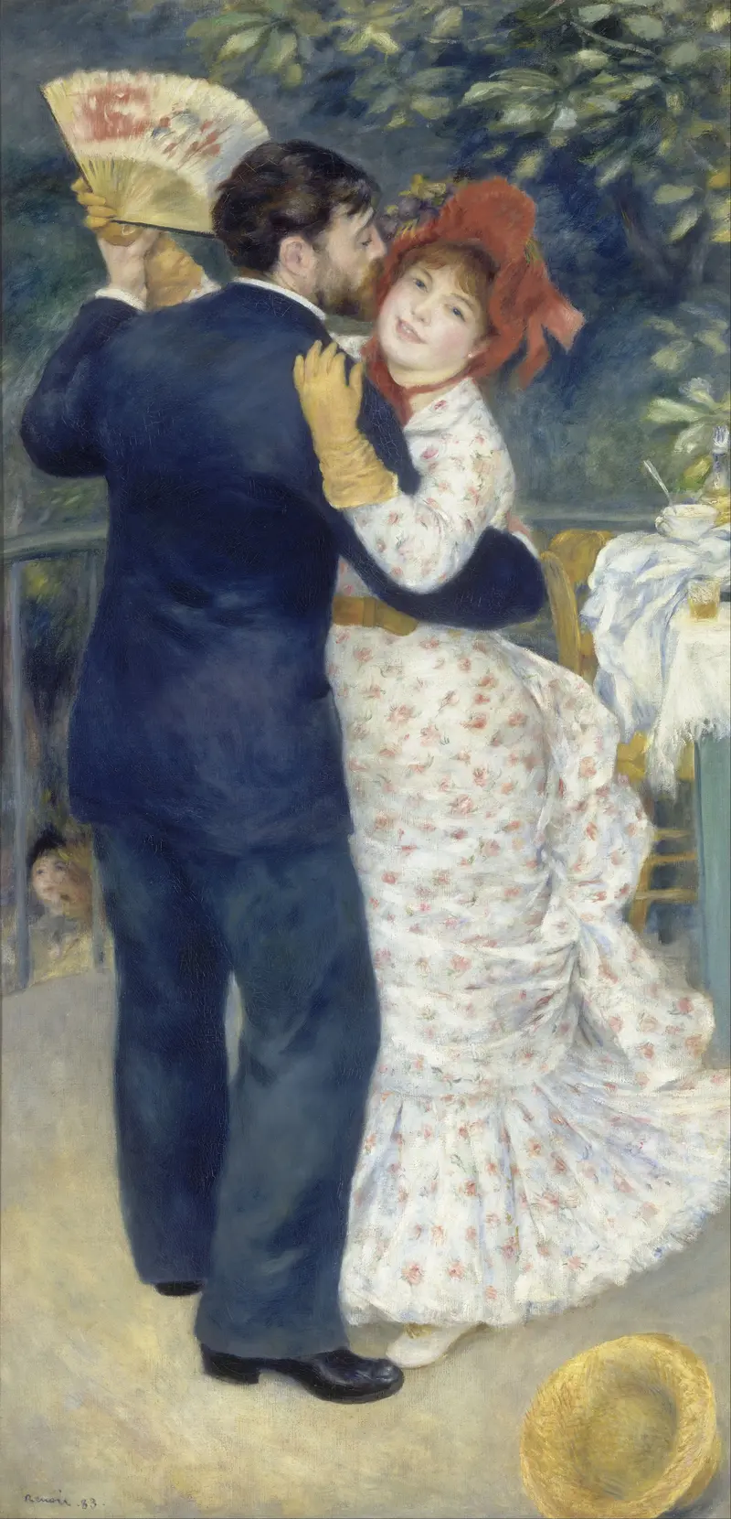 A life-size couple dances closely beneath a tree, the man in a dark blue suit and the woman in a white dress with pink flowers and a red hat, holding a fan.