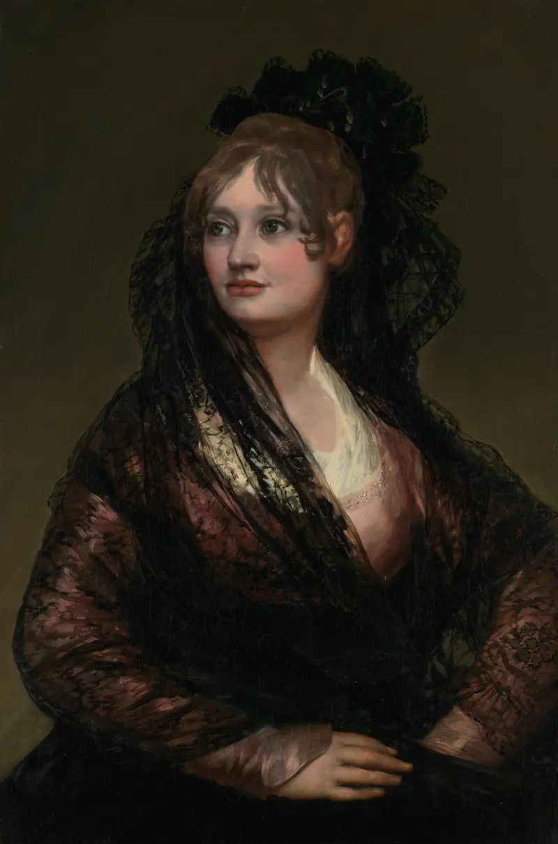 A young woman with chestnut hair wears a sheer black mantilla and white blouse, seated against a muted olive-brown background, looking left with a composed expression.