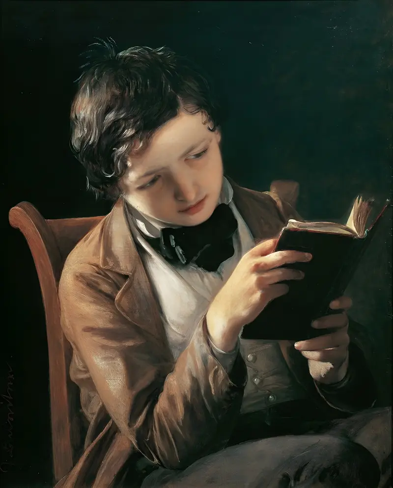 A young boy deeply engaged in reading, showcasing a moment of quiet concentration.
