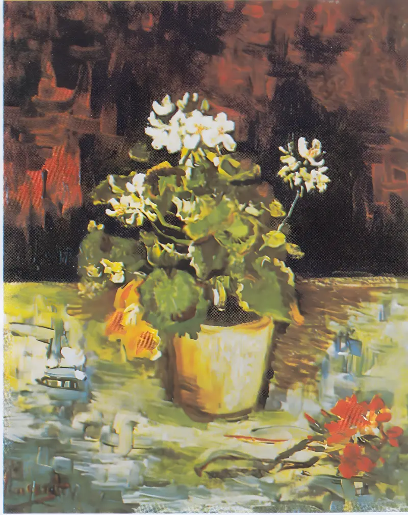A geranium plant with green leaves and white blossoms sits in a yellowish flowerpot on a colorful, textured tabletop with scattered red flowers nearby.