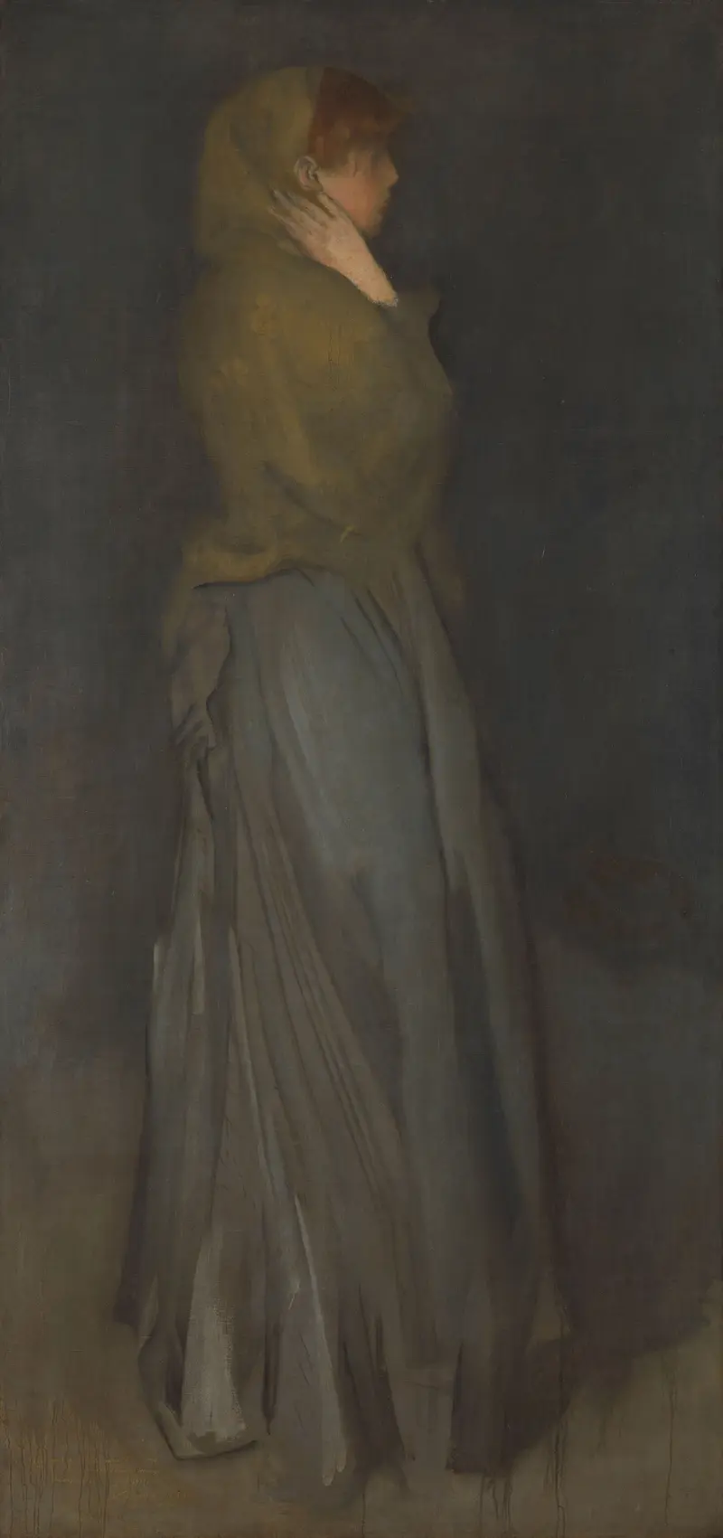 A woman in yellow and gray stands in a shadowy background, her profile turned away, hand at her neck in a moment of reflection.