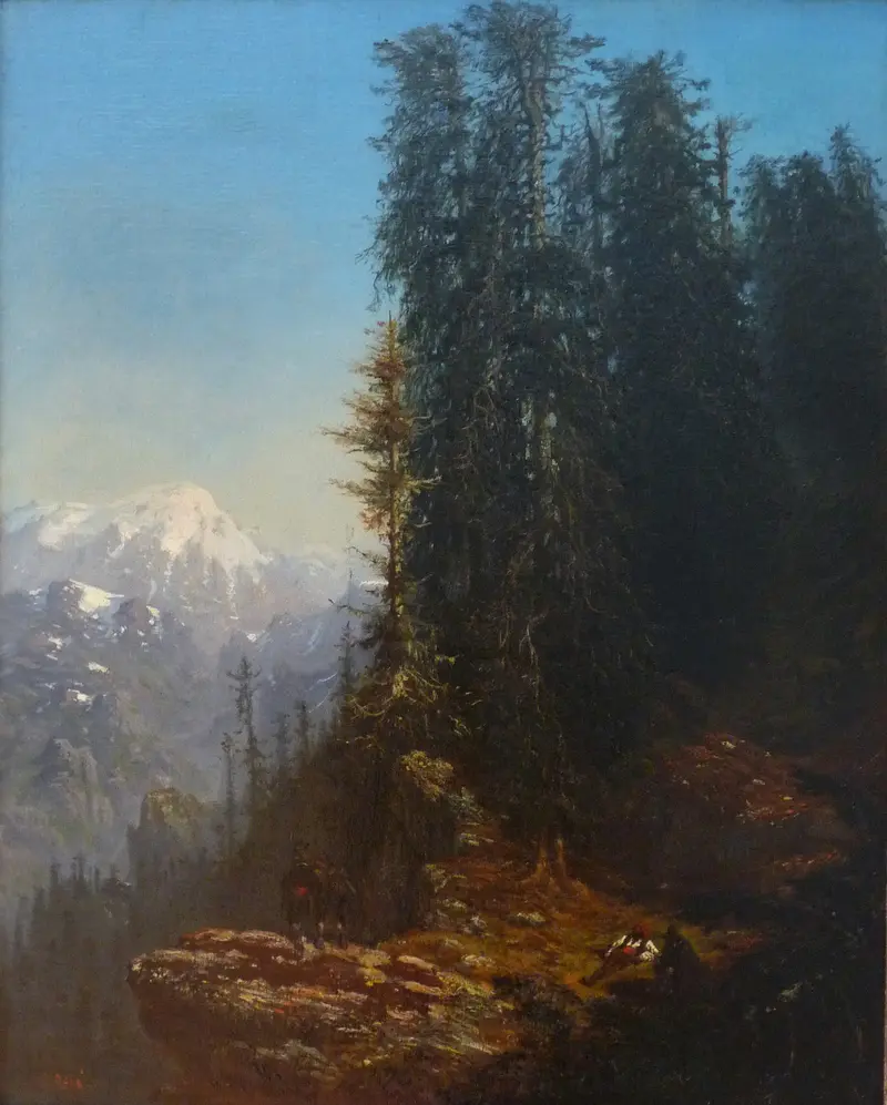 A rocky slope illuminated by sunlight with dense dark evergreen trees on the right and distant snow-capped mountains under a clear blue sky.