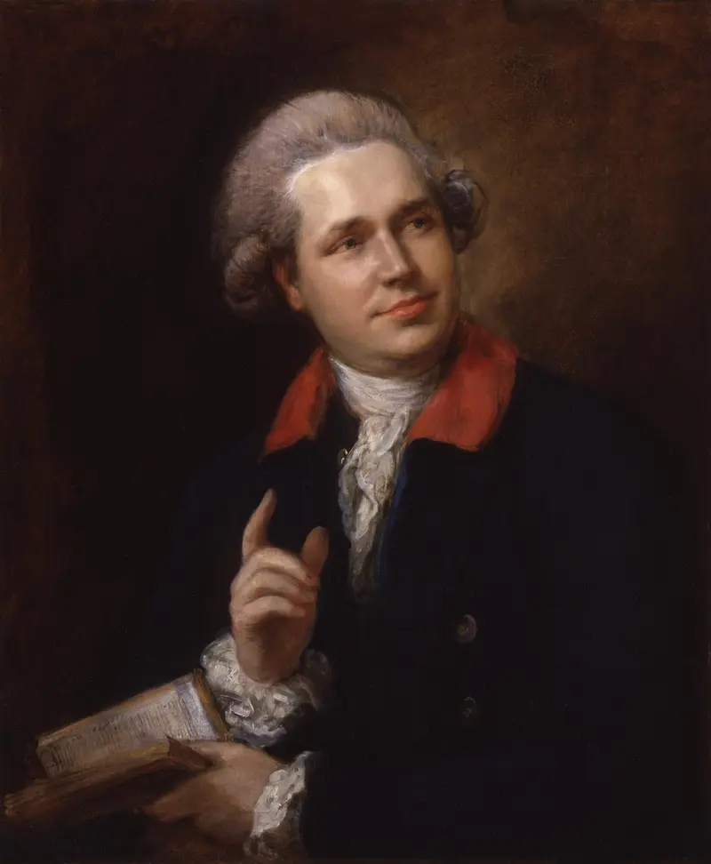 A man with a raised finger and thoughtful gaze, holding an open book, dressed in a stylish outfit with a red collar.
