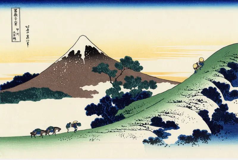 A snow-capped Mount Fuji rises behind a green hillside where travelers and horses ascend a winding path under a blue to pale yellow sky.