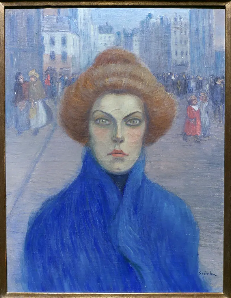 A woman with a striking expression framed by voluminous hair, set against a blurred city background.