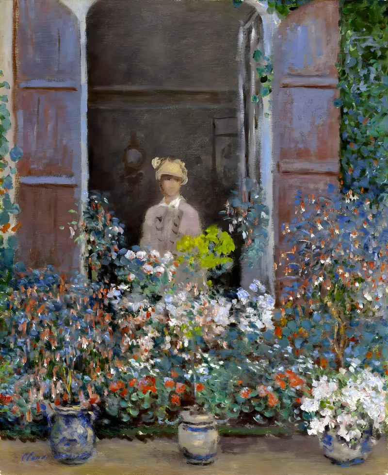 A woman in a pale dress and hat stands behind a window with open blue shutters, surrounded by colorful flowering plants in pots and beds.