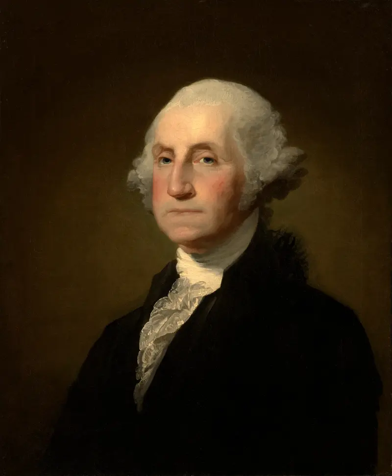 A man with powdered white hair in a black coat and white lace jabot is seated against a dark, plain background, his face softly illuminated.