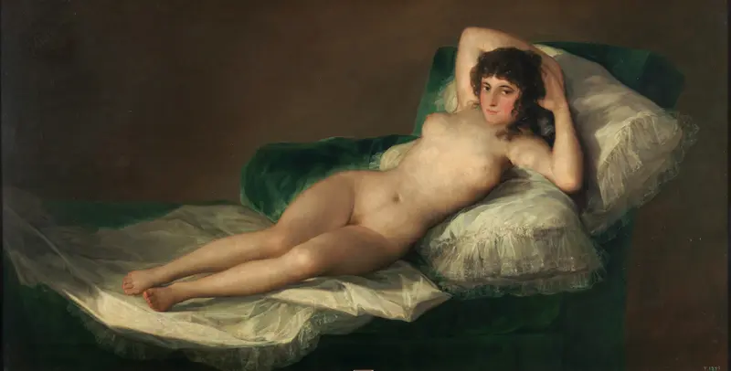 A nude woman reclines diagonally on a green velvet fainting couch with white lace-trimmed pillows and white sheets against a muted brown background.